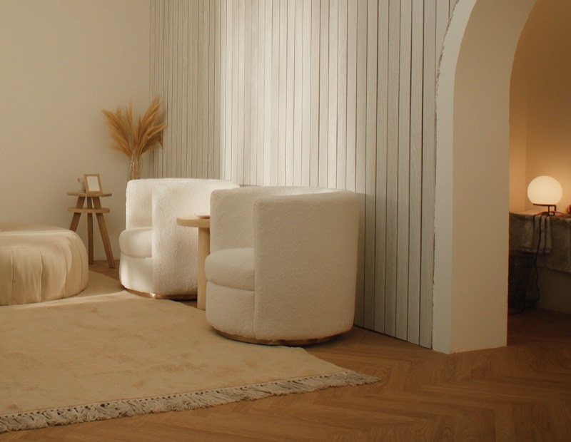 The studio lounge — linen armchairs, warm lamplight, and an arched doorway