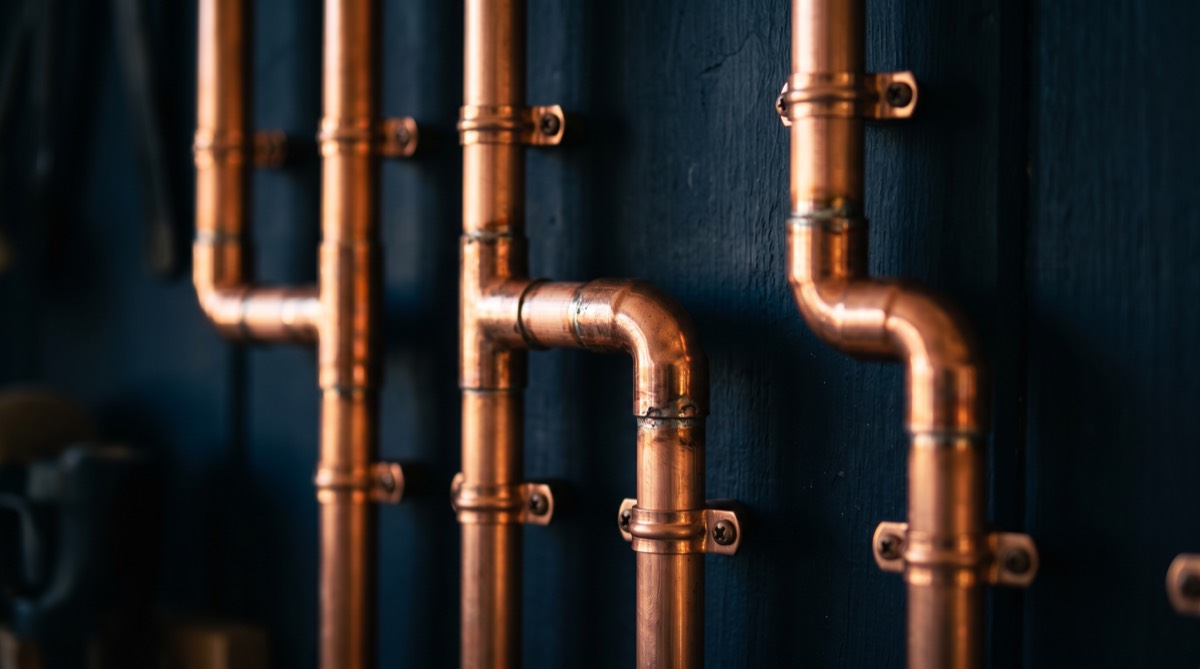 Neat copper pipework against a dark navy wall in the Summit workshop