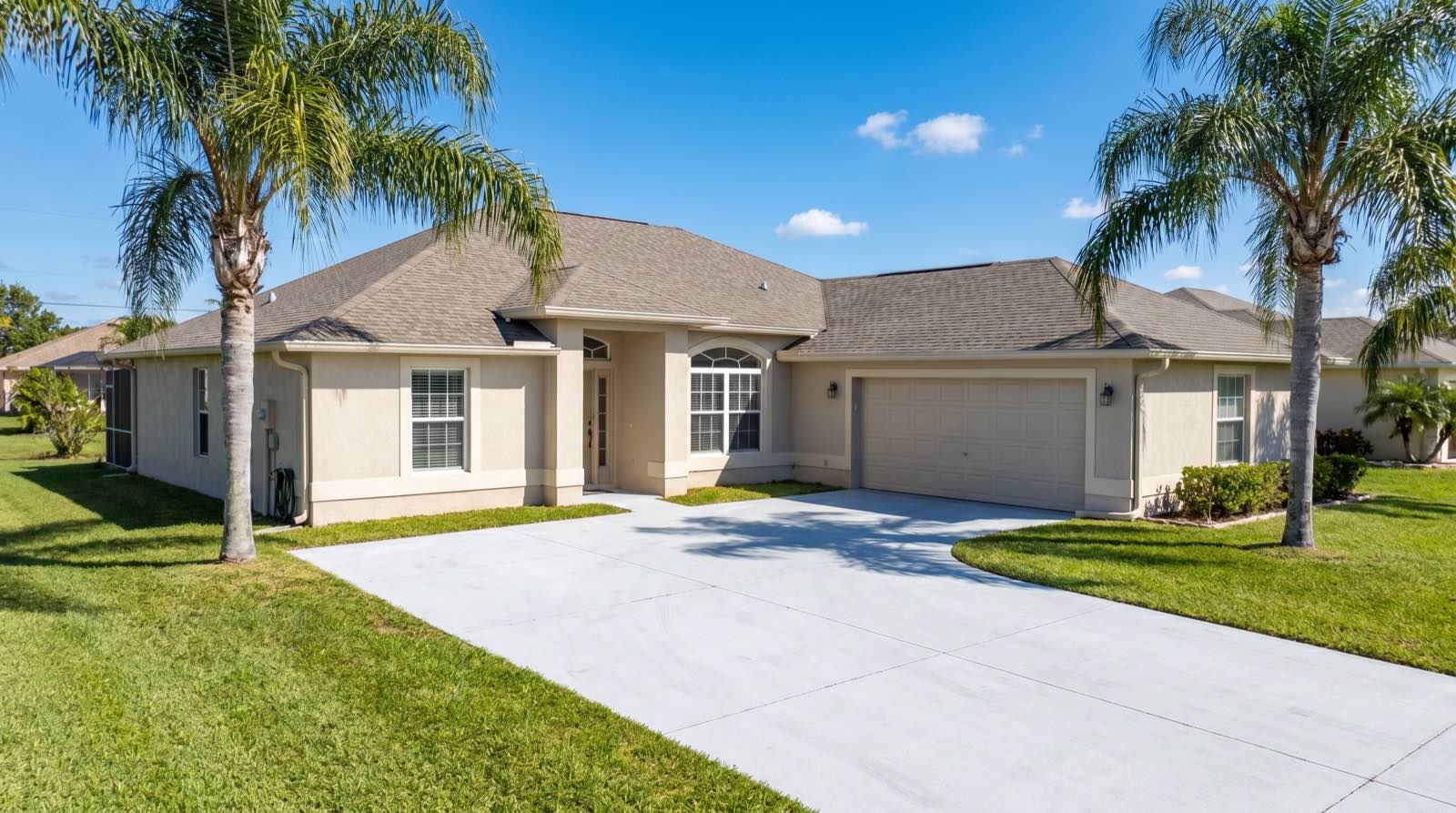 A freshly pressure-washed Davenport home: bright white driveway, clean stucco and spotless roof under a blue Florida sky